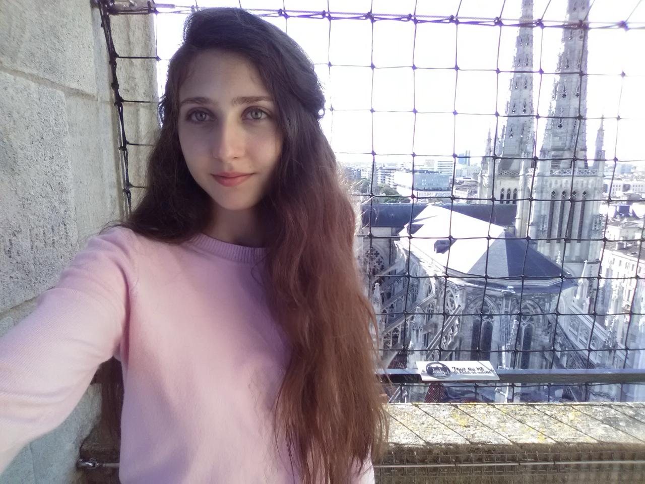 Татьяна Смагло на смотровой площадке; за сеткой&nbsp;— шпили готического собора